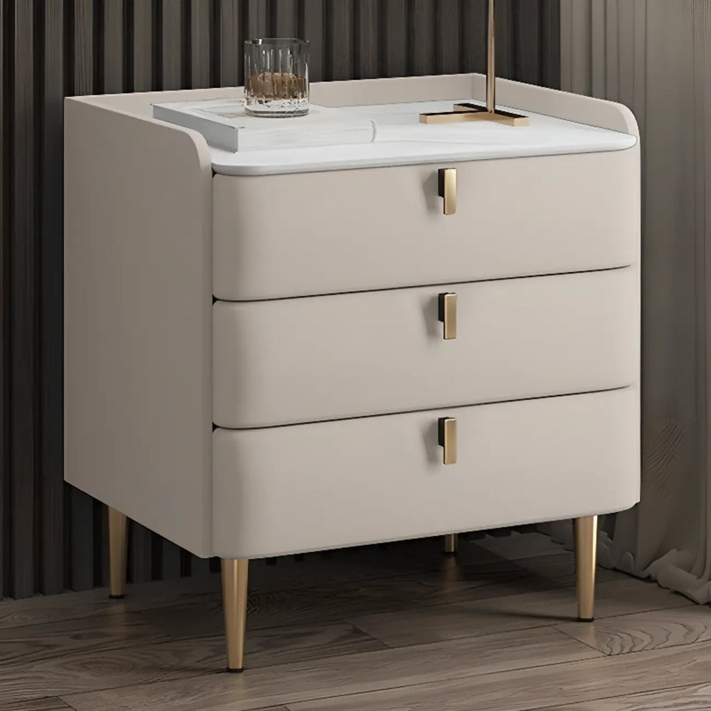 Table de chevet moderne à 3 tiroirs avec plateau en pierre, finitions dorées et revêtement en cuir.