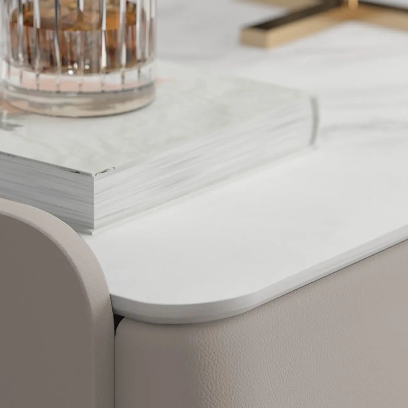 Table de chevet moderne à 3 tiroirs avec plateau en pierre, finitions dorées et revêtement en cuir.