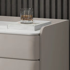 Table de chevet moderne à 3 tiroirs avec plateau en pierre, finitions dorées et revêtement en cuir.