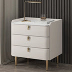 Table de chevet moderne à 3 tiroirs avec plateau en pierre, finitions dorées et revêtement en cuir.